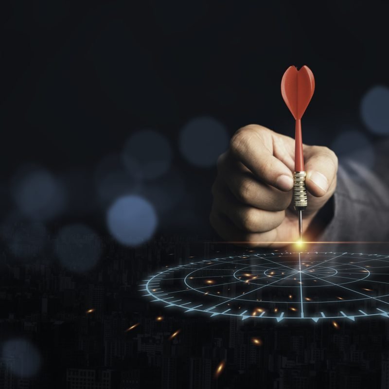 Businessman throwing red arrow dart to virtual target dart board. Setup objectives and target for business investment concept.